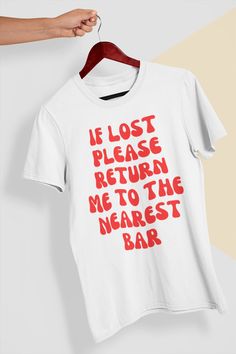 Get ready to make a statement with this hilarious "If Lost, Return Me to the Nearest Bar" t-shirt. Perfect for any party animal, this shirt is the perfect accessory for a night out with friends or a casual day out. Made from soft, comfortable cotton, this shirt will keep you looking and feeling great all day long. Whether you're a beer lover, wine enthusiast, or just love a good cocktail, this shirt is the perfect way to show off your love for a good time. With its unique design and clever messa Drinking Tshirt Ideas, Bar Tshirt Ideas, Fun Slogan Crew Neck Top, Band Merch Shirt With Funny Print And Crew Neck, Band Merch Crew Neck Top With Funny Text, Funny Text Crew Neck Top, Funny Crew Neck Top With Text, White Band Merch Top With Funny Text, Funny Red Screen Printed Top