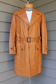 "McGregor leather US Size 42, labeled '42' (please rely on measurements provided) 1970's 'New Old Stock'. 'Leathercraft' care hang tag Wow! This is a first for Style Stash. A deadstock leather overcoat. Butterscotch color leather that is soft and supple. Double stitched seam work. Faux wood grain buttons. Blackens steel buckle and 'D' rings. Made in Brasil. Super 70's styling. Massive 6\" notched lapel. 3 button closure. Scalloped yoke, front and back. Natural shoulder with a funky shoulder stra Retro Leather Outerwear For Formal Occasions, Vintage Longline Leather Jacket, Vintage Leather Business Outerwear, Vintage Leather Outerwear For Business, Vintage Long Leather Jacket For Business, Vintage Belted Outerwear For Formal Occasions, Belted Vintage Outerwear For Formal Occasions, Vintage Long Leather Coat, Vintage Long Leather Jacket