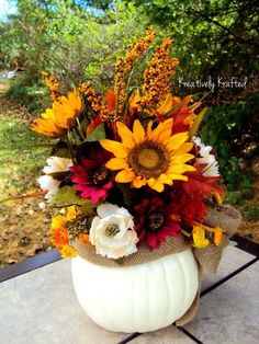 a vase filled with lots of flowers on top of a wooden table covered in burlocks