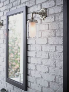 a bathroom mirror mounted to the side of a brick wall