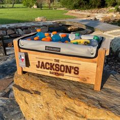 a wooden box filled with drinks sitting on top of a rock