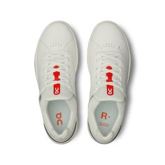 a pair of white sneakers with red lettering on the soles and bottom laces