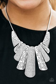 a woman wearing a black shirt and a silver necklace with intricate designs on it's neck