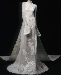 a white wedding dress on display in front of a black background