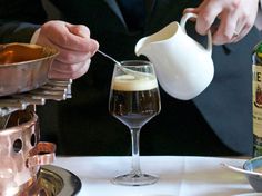 a person pouring some liquid into a wine glass