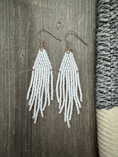 Earrings: Handmade beaded fringe earrings. Color and design: Matte white and tan colors in a feathery fringe shape.   Hooks: High quality hypoallergenic titanium commercial pure grade 1 ear wires (feels so comfortable for even the most sensitive skin).  Beads: High quality 11/0 czech ceramic seed beads (very lightweight).  Size: 1" (inch) width x 3.5" (inch) drop. White Beaded Fringe Long Drop Earrings, White Long Drop Beaded Fringe Earrings, White Long Drop Jewelry With Beaded Fringe, White Bohemian Fringe Earrings, White Beaded Tassel Drop Earrings, White Bohemian Beaded Earrings With Tassels, Bohemian White Beaded Earrings With Fringe, Bohemian White Tassel Earrings With Beaded Fringe, Bohemian White Beaded Fringe Tassel Earrings