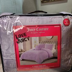 a piece of luggage sitting on top of a bed covered in purple comforter and pillows