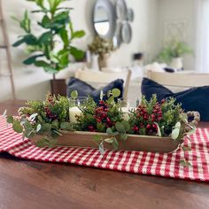 a wooden tray filled with greenery on top of a red and white checkered table cloth