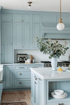 a kitchen with blue cabinets and marble counter tops, an island in the middle has flowers on it