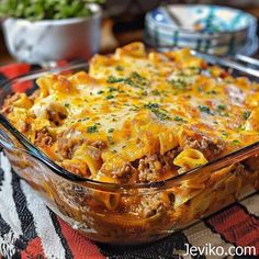 a casserole dish with meat and cheese in it on a patterned tablecloth