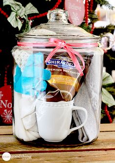 a glass jar filled with various items on top of a wooden table next to a christmas tree