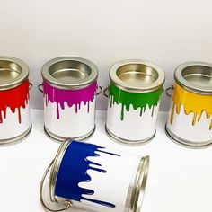 four paint cans with different colors on them and one has a can opener in the middle