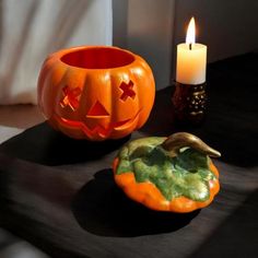 two carved pumpkins sitting next to each other on a table with a lit candle