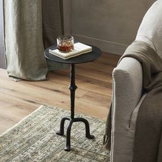 a small table with a drink on it in front of a couch and window sill