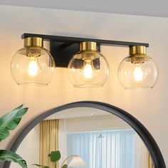 a bathroom vanity light with three clear globes