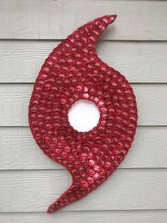 a red sculpture on the side of a white building with a circular hole in it