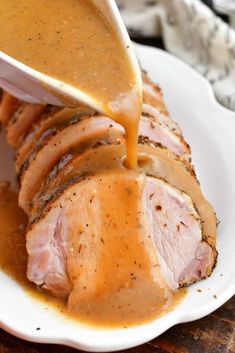 someone pouring gravy on pork loin in a white plate with the words juicy & tender pot - roasted pork loins