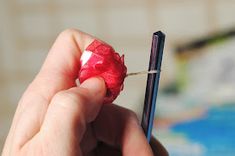 a person holding a piece of red paper with a toothpick sticking out of it