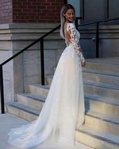 a woman in a wedding dress standing on the steps with her back to the camera