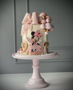 a minnie mouse cake with balloons and decorations