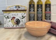 an empty bowl sitting on top of a counter next to some olives and seasonings