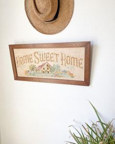 a hat is hanging on the wall next to a sign that says home sweet home