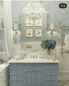 a blue and white bathroom with chandelier above the bathtub, sink, and mirror