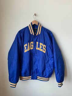 Up for sale is this Holloway "EAGLES" Blue and Gold Satin Bomber Jacket size XL. This jacket is in EXCELLENT condition as you can see from the photos.   The item will ship one business day after the payment is received. Blue Spring Outerwear For College, Retro Blue Hooded Varsity Jacket, Blue Retro Hooded Varsity Jacket, Blue Hooded Retro Varsity Jacket, Retro Long Sleeve Outerwear For College, Retro Blue Winter Outerwear, Vintage College Outerwear With Pockets, Vintage Outerwear With Pockets For College, Retro Outerwear With Pockets For College