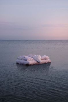 an inflatable mattress floating on top of the ocean at sunset or dawn,