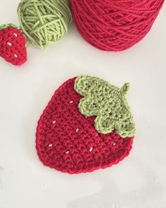 crocheted strawberries and two balls of yarn