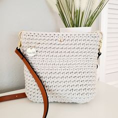 This charming boho crossbody bag is petite yet roomy.  It's just the right size to hold your everyday essentials for a fuss-free day out.  It is lightweight at 15 ounces empty, with a perfect adjustable leather strap. Lovingly crocheted by hand, this bag is one of a kind. Whether you're stepping out for a casual outing or headed to a chic brunch, this small crossbody bag is ready to compliment any outfit with charm.  This bag is extremely durable and eco-friendly, crocheted with 100% recycled 5mm cotton cord.  The brown leather strap is adjustable and the bag includes a magnetic snap closure.   COLORS This beautiful crossbody bag is available in beige with adjustable brown leather strap.  MEASUREMENTS 8 INCHES HIGH 8 INCHES WIDE STRAP  IS ADJUSTABLE from 43 inches to 51 inches in length MA Handmade Crochet Crossbody Bag For Gift, Handmade Crossbody Crochet Bag For Gift, Handmade Crochet Crossbody Bag As Gift, Handmade Cream Crossbody Bag, Rectangular Crochet Bag With Adjustable Strap As Gift, Chic Handmade Cream Crossbody Bag, Crochet Shoulder Bag As Gift, Crochet Crossbody Shoulder Bag For Gift, Everyday Crochet Crossbody Bag With Leather Handles