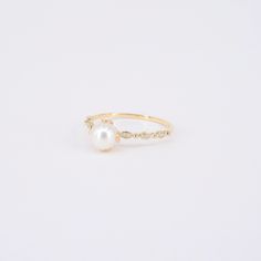 a pearl and diamond ring on a white background