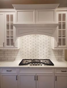 a stove top oven sitting inside of a kitchen next to white cabinets and cupboards