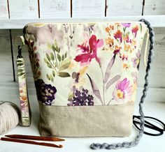 a purse sitting on top of a white shelf next to knitting needles and yarns