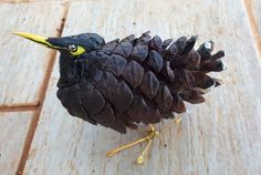 a pine cone shaped like a bird sitting on top of a wooden floor