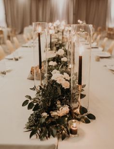 a long table with candles, flowers and greenery is set up for a wedding reception