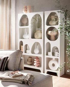 a living room filled with lots of furniture and vases on top of white shelves