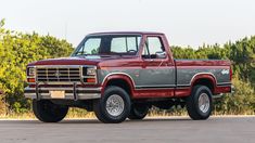 a red pick up truck parked in front of some trees