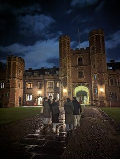 some people are standing in front of an old building at night with the lights on