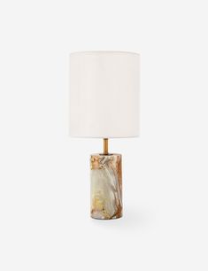 a marble lamp with a white shade on it's side and a gold base