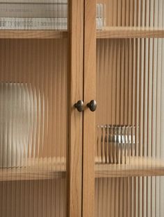 a wooden cabinet filled with glass plates and silverware next to a wall mounted bookcase