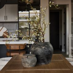 two vases sitting on top of a wooden table next to a planter filled with flowers