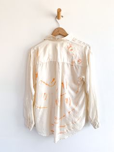 a white shirt with orange designs hanging on a wall