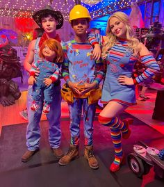 two women and one man are posing for a photo in front of costumes on stage