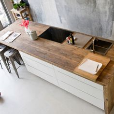 the kitchen counter is made out of wood and has two sinks on one side, with an island in the middle