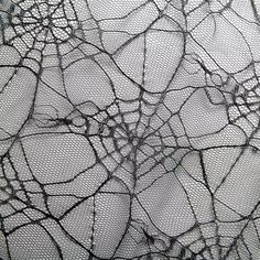 an intricate pattern made up of black net on white fabric, with small holes in the center