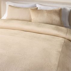 a bed with beige sheets and pillows on top of it