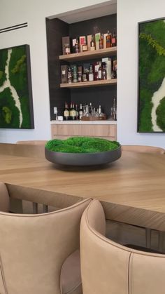 a table with two chairs and a bowl on it in front of some shelves filled with bottles