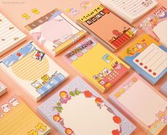 many stationery papers are arranged on a pink surface with cartoon characters and other items