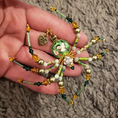 a hand holding a green and gold beaded necklace